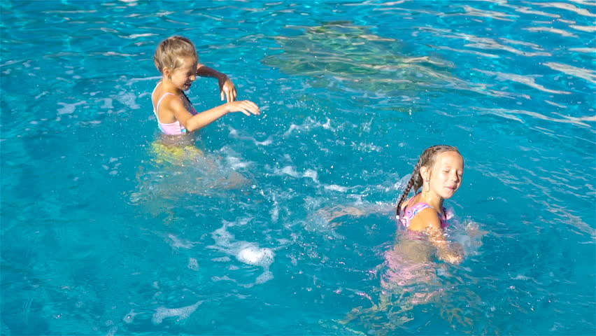 Adorable little girls having fun in outdoor swimming pool. SLOW MOTION VIDEO | Shutterstock HD Video #1019551114