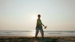 Silhouette of senior woman practicing tai chi balloon ball with racket on the beach at sunset, slow motion - Powered by Shutterstock - Get 15% off with code: PIKWIZARD15