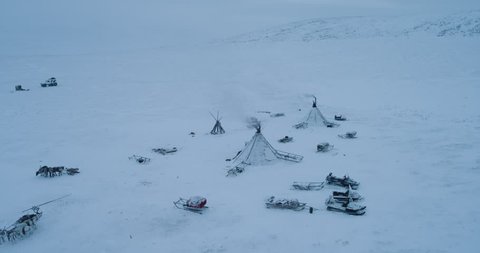 In the Arctic people living in yurts video taking of drone , reindeers with sleigh are driving around the yurts amazing video.