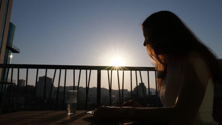 Woman have light healthy breakfast, sitting on balcony at early morning. Bright sun on background, girl take piece of salad and then drink water from glass | Shutterstock HD Video #1019584177