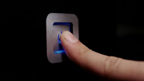 Male finger presses the blue LED power button on the computer