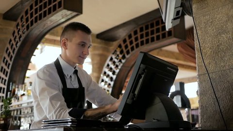 Man or waiter in apron at counter with cashbox working at the restaurant