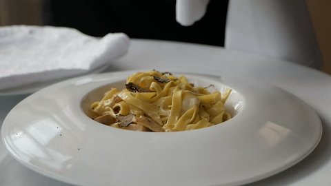 Chef grates truffle on pasta in Italian restaurant