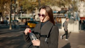 thirsty business woman opening bottle and drinking water outdoors. Slowmotion shot