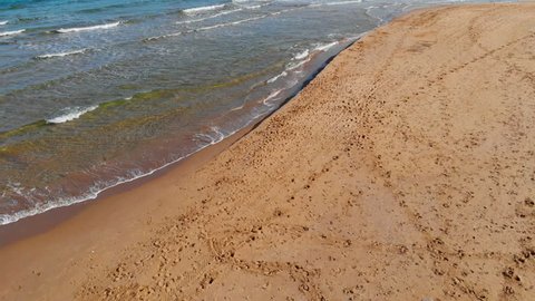 Transparent waves roll on a sandy beach in  sunny day