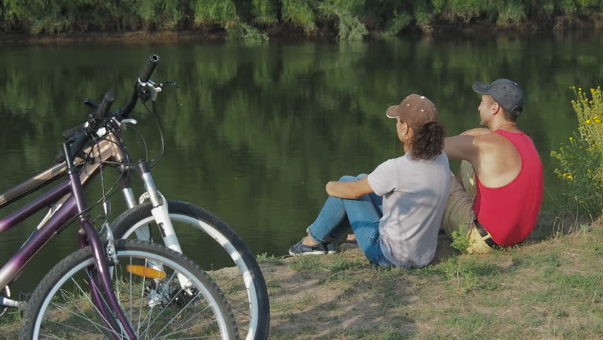Married couple with bicycles in nature. Cyclists enjoy the river landscape.