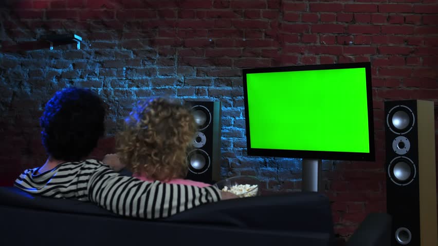 Man and woman watching green screen TV