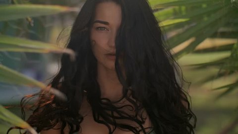 Beautiful Girl in Bikini against Tropical Background. Stunning slow motion footage of tropical paradise woman. Close-up of sensual young brunette mixed race Asian Caucasian woman wearing swimsuite