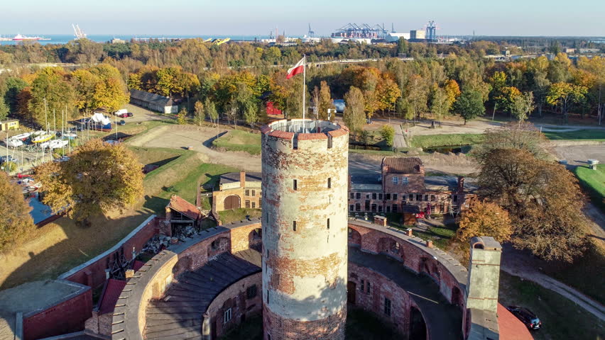 Medieval Wisloujscie Fortress with old lighthouse tower in port of Gdansk, Poland. A unique monument of the fortification works. Aerial view at sunset. Exterior Northern  Gdansk port in the background