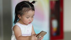 A cute happy little girl Asian using smartphone Which is bad for the development of children. And harmful to the baby's eyes.