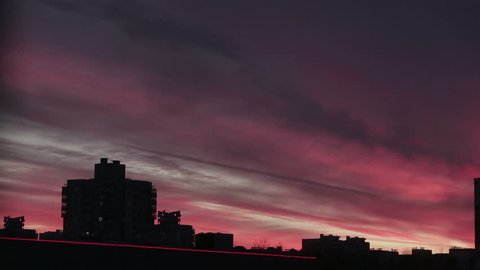 Beautiful pink sunset on the background of buildings. Time lapse. Gradual attenuation.