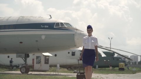 Beautiful, cheerful, young and smily stewardess walks towards the camera