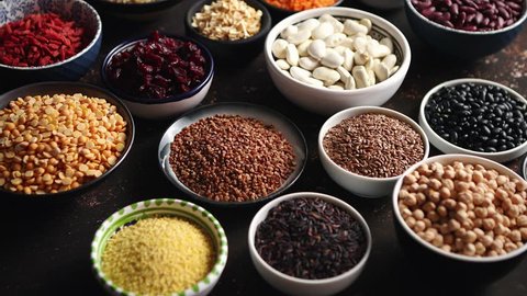 Various superfoods in smal bowls on dark rusty background. Superfood as rice, lentil, beans, peas, goji, flaxseed, buckwheat, couscous, chickpeas Above view Flat lay