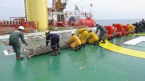 Terengganu, Malaysia: November 10, 2018 - Oil and gas workers roll the helideck net and preparation works to lift it up using the crane in oil platform in Terengganu, Malaysia.
