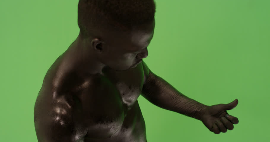 Man covered in black as if burnt looking up at sky against green screen in slow motion