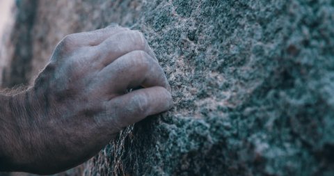Close up on climber hand and fingers on rough granite rock