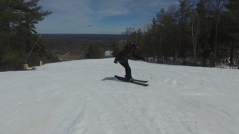 Female freestyle skiier cruises down hill backwards