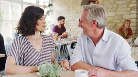 Mature couple laughing and talking while drinking coffee at a table in a restaurant, selective focus - Powered by Shutterstock - Get 15% off with code: PIKWIZARD15