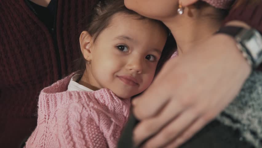 Close up of happy family hugging at porch and enjoying hot chocolate on Christmas evening in slow motion. Girl smiling at camera