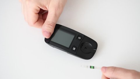 Glucometer for measuring glucose level blood close-up on a white background. Medicine, diabetes, glycemia, health care and people concept