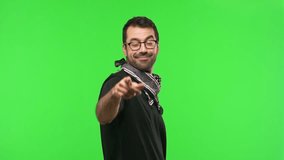 Man with glasses on green screen chroma key background points finger at you with a confident expression