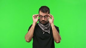 Man with glasses on green screen chroma key background makes funny and crazy face emotion