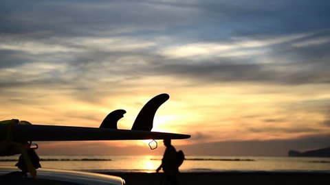Surfboard on a car rooftop by the sea at sunset in Alghero. Sardinia, Italy