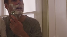 Handheld shot of father and son reflecting on mirror while shaving in bathroom - Powered by Shutterstock - Get 15% off with code: PIKWIZARD15