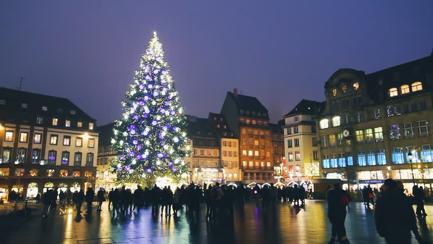 Christmas market in Strasbourg with tall beautiful illuminated tree in old town square, footage at night in winter with city lights and decorations, European tradition, Alsace
