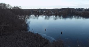 Aerial video of fishermen on first ice on river. Thin river ice with reflections as in mirror