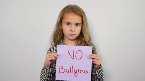 Teenage girl holding paper with inscription no bullying. Studio shot 
