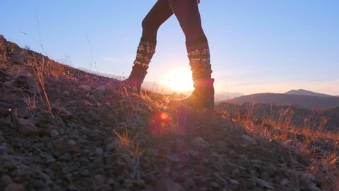Close up of feet female hiker traveler woman walking and climbing up in rocky top mountain at sunset. foot steps of climber. nature, travel tourism tourist hiking. legs in trekking boots. slow motion
