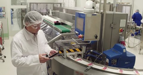Medecine specialist using digital tablet while taking inventory in pharmaceutical factory.
