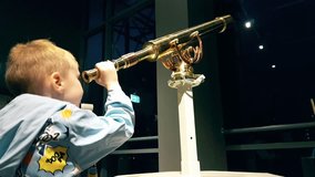Little caucasian boy looks through a telescope into the dark sky, child plays astronomer close-up, stock video