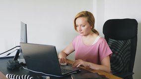 beautiful young woman working on a laptop and computer while sitting at a desk.