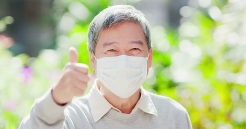 old man smile show thumb up and wear mask with nature green background