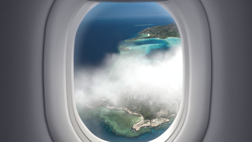 View from the window at passenger seat in airplane flight above clouds and sea with tropical islands