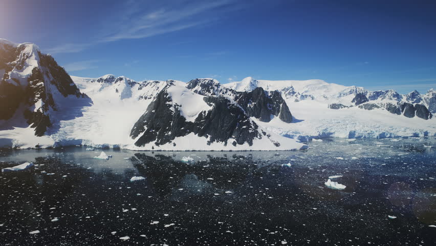 Aerial Flight Over Snow Mountains. Antarctica Shoreline. Drone View Of Snow, Ice Covered South Pole Surface, Cold Ocean. Amazing Winter Background. Lemaire Channel. 4k Footage.