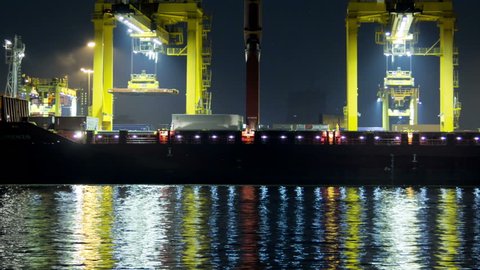 Time Lapse: Container Cargo freight ship with working crane bridge in shipyard at night
