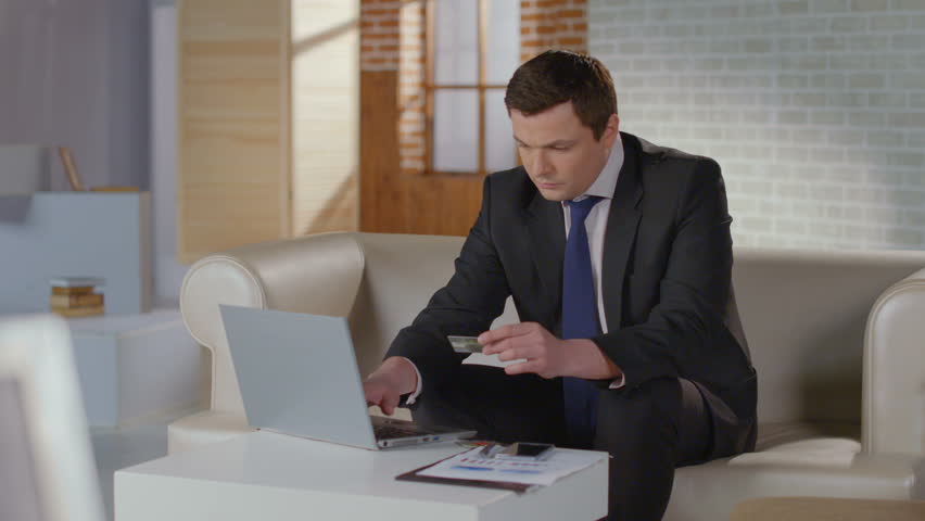 Rich man business suit inserting credit card number on laptop