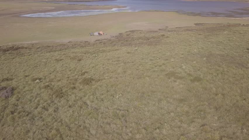 Aerial view of tents at a shallow lake, Tasmania, Australia. 4K, D-Log.