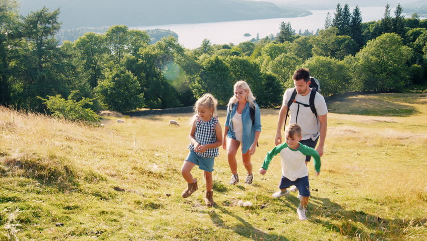 Slow Motion Shot Of Family Climbing Hill On Hike Through Countryside In Lake District UK Together