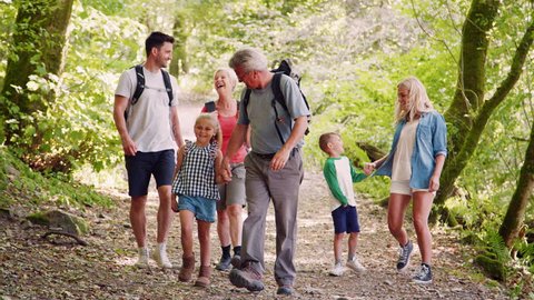 Slow Motion Shot Of Multi Generation Family Walking Towards Camera Along Woodland Path Together