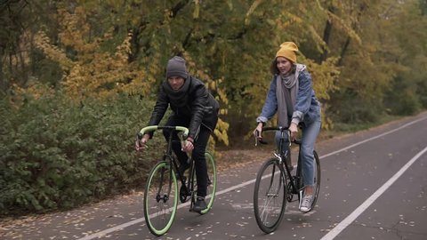 Two bicycle. Couple on bikes. Romantic biking in the autumn city park. Man and woman riding bikes. Active friends leisure. Slow motion