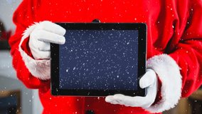 Digital composite of Video composition with snow over torso of  santa holding tablet