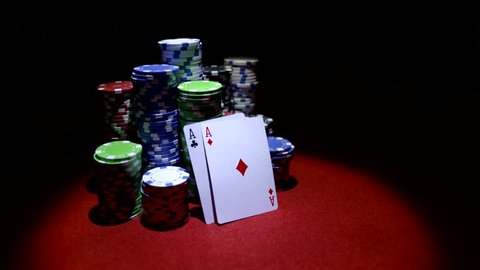 Pair of aces  and poker chips on red casino table