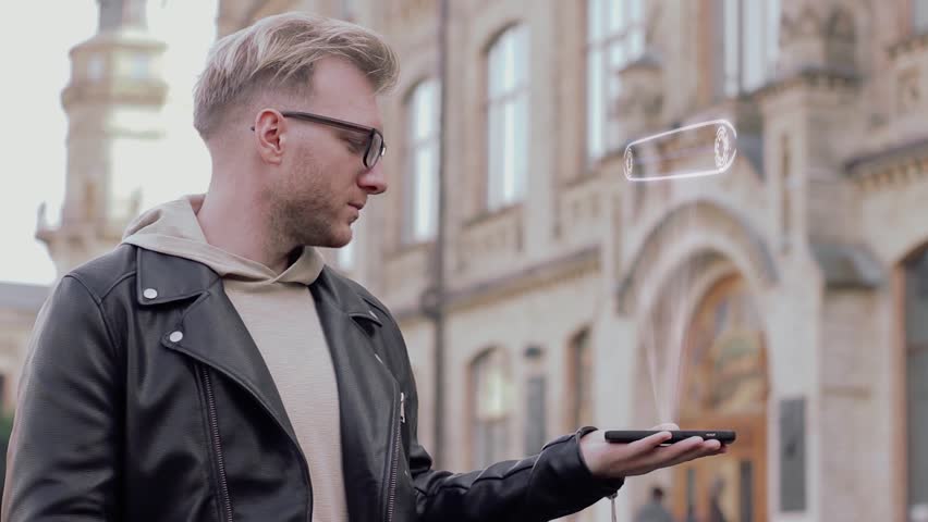 Smart young man with glasses shows a conceptual hologram Machine Learning. Student in casual clothes with future technology mobile screen on university background Royalty-Free Stock Footage #1019746585