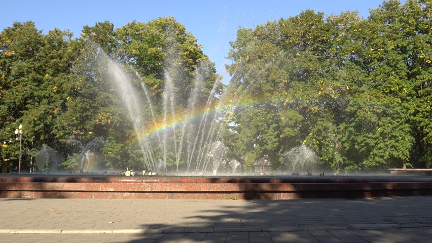 City fountain with a rainbow among the trees in the resort town in the fall in the foothills of the Caucasus