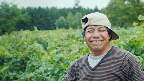 Portrait of a smiling mexican farmer. Standing on the field, looking at the camera