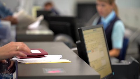 airport employee checking passport of people passengers on border and selling tickets in airport counters. check-in on board aircraft, close up, close-up, Checking passports at the airport check in.